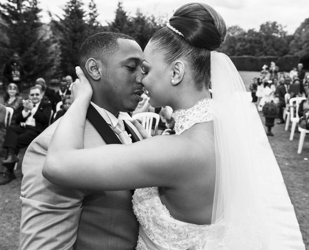 Mariés sur le point de s'embrasser pendant une cérémonie de mariage en extérieur, en noir et blanc