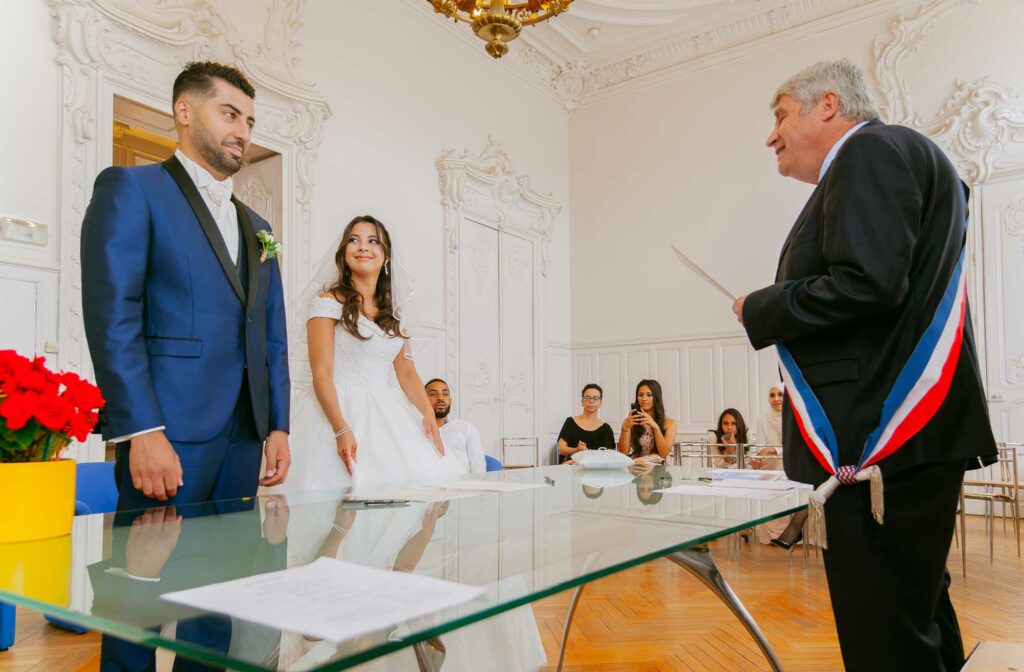 Marié debout devant l'élu, tandis que sa femme le regarde pendant la cérémonie à la mairie