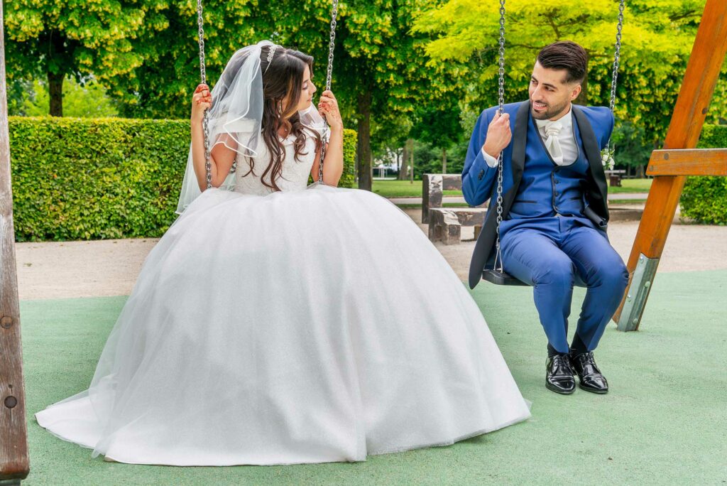 Couple de mariés se regardant sur une balançoire dans un parc