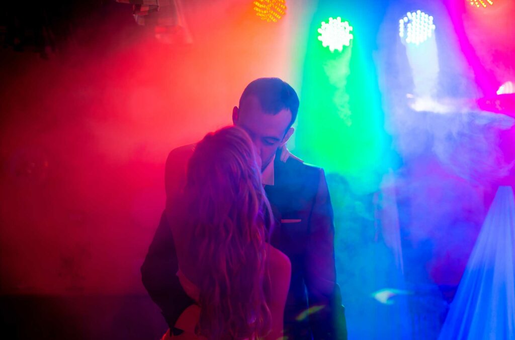 Mariés dansant ensemble sous des lumières colorées pendant la soirée